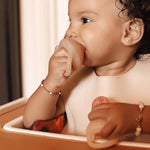 Baby playing with a self feeding pacifier indoors