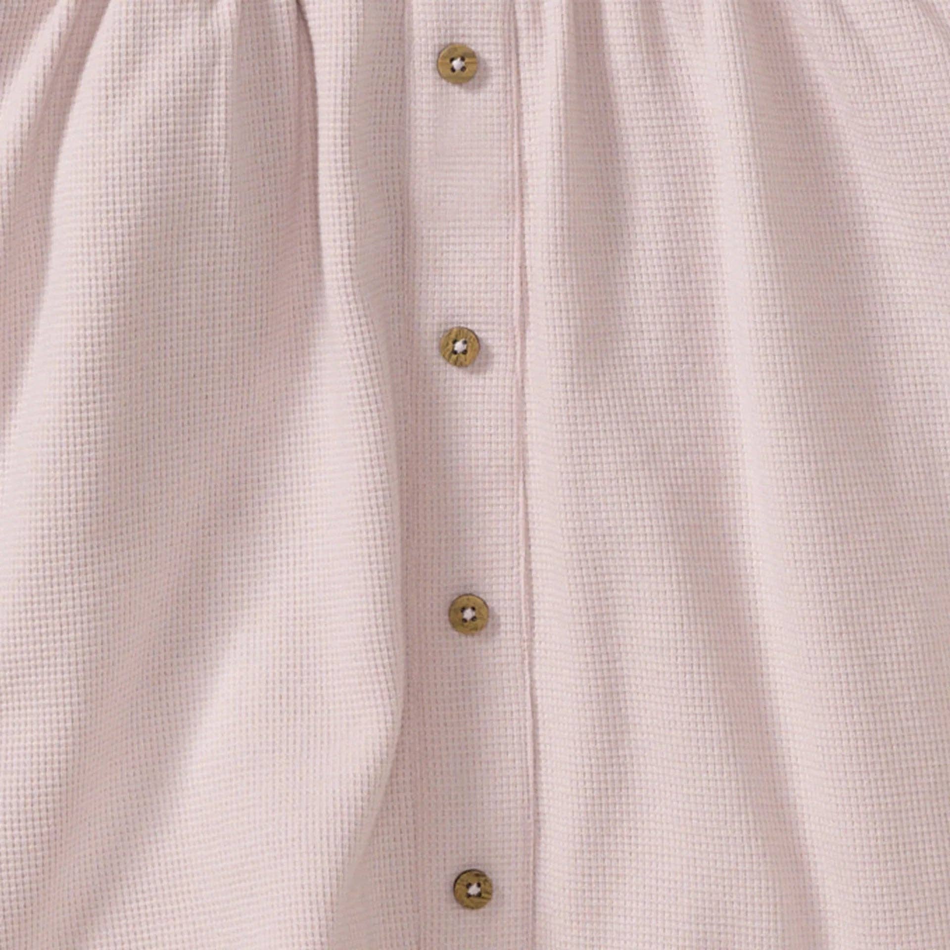 Close-up of a light pink dress with button details
