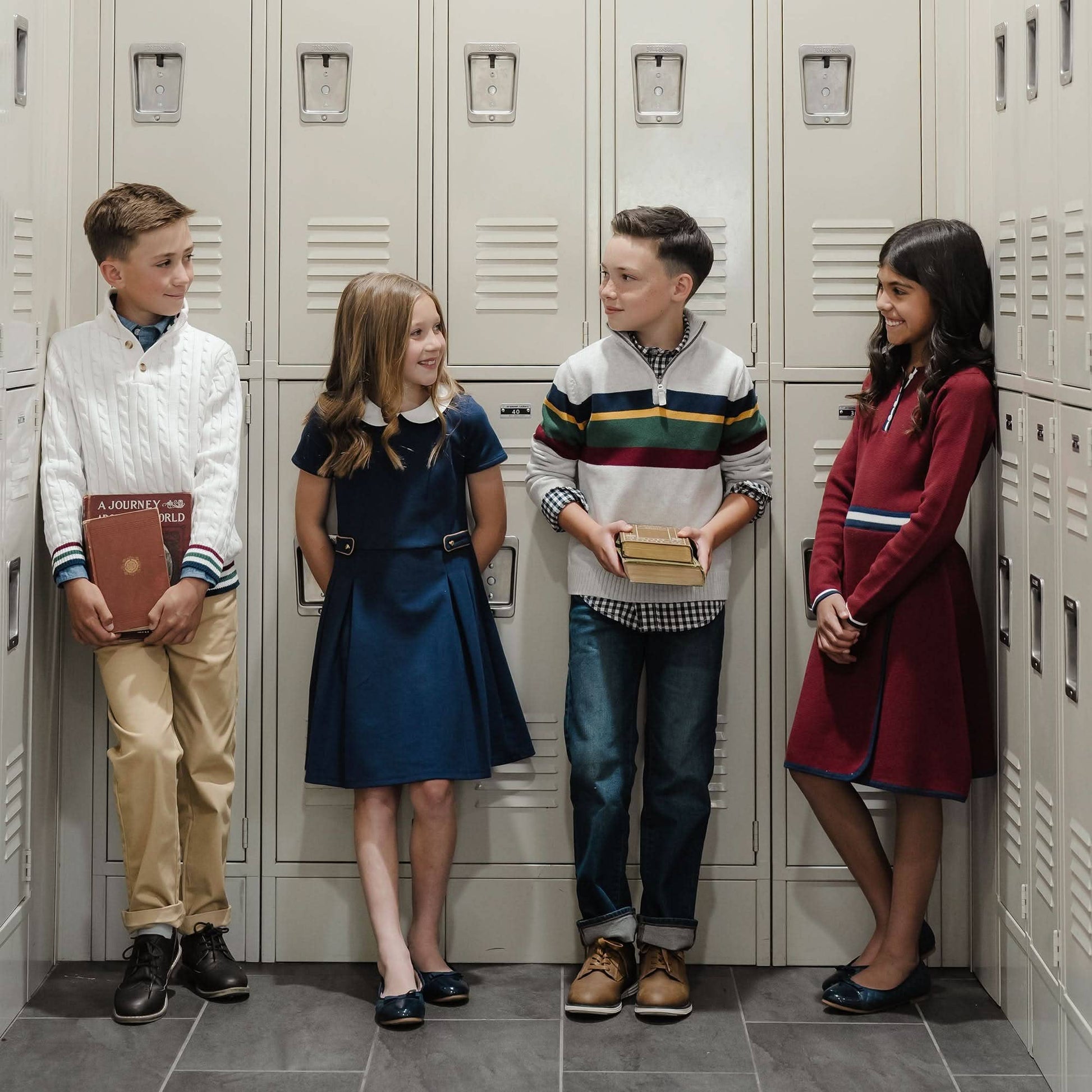 Four children standing in front of lockers wearing Hope & Henry clothing.