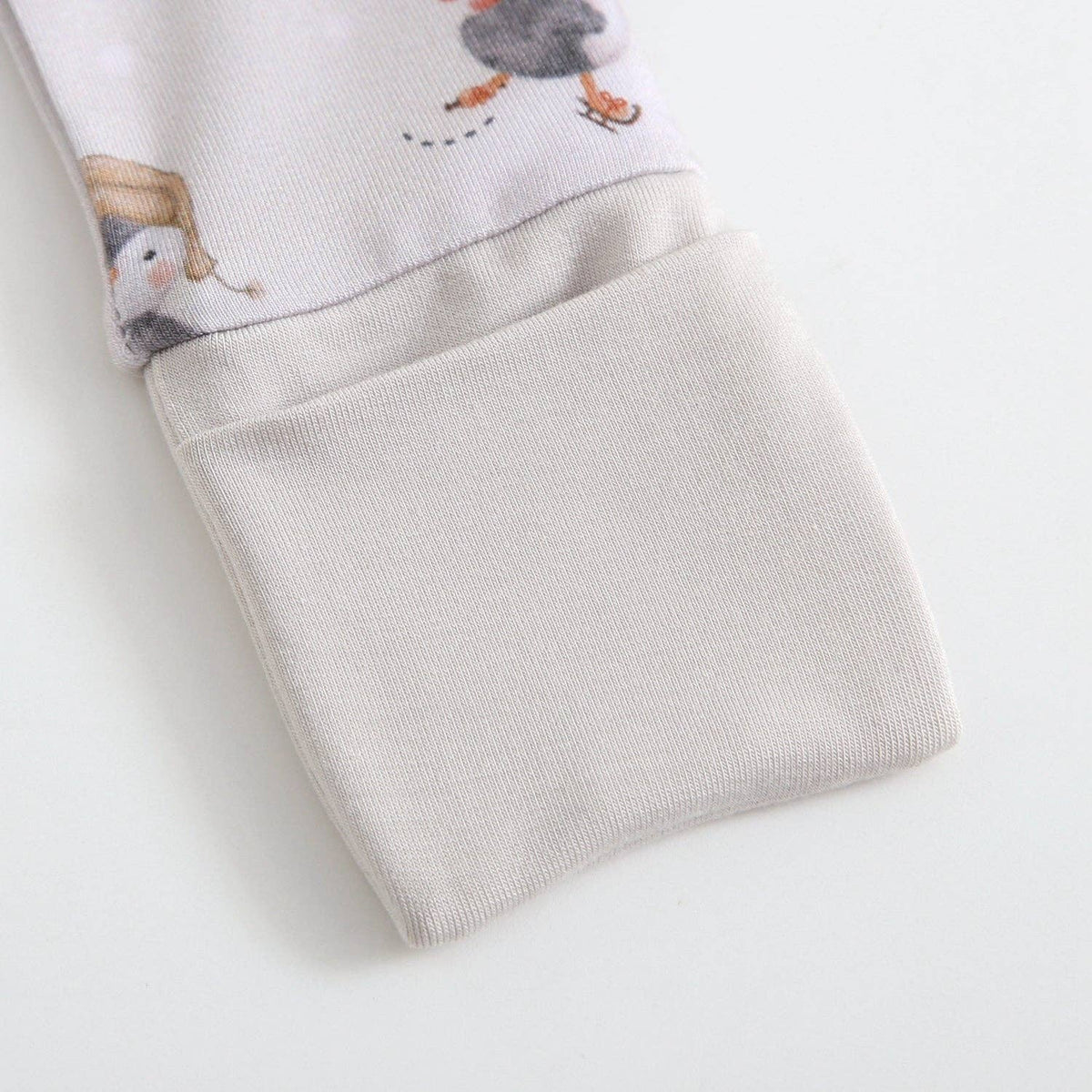 Folded baby romper with cartoon penguin design on a light gray background