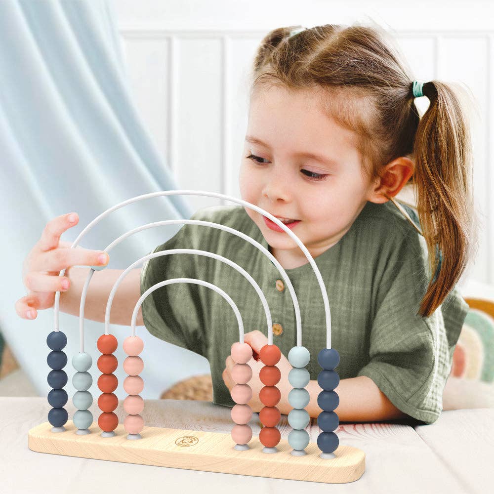Child playing with a colorful abacus toy indoors.