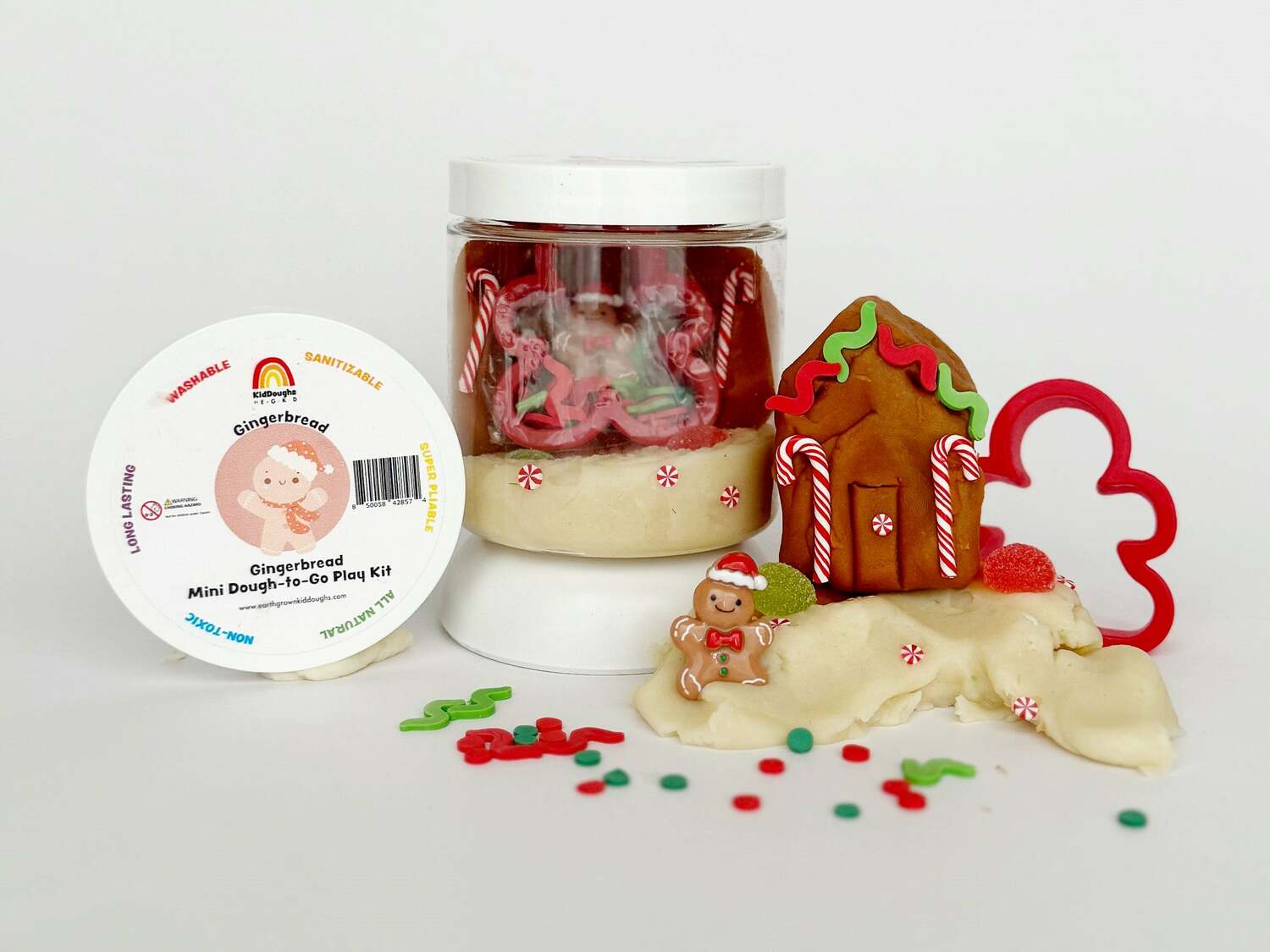 Gingerbread-themed play dough set with a jar, gingerbread house, and cookie cutter on a white background.