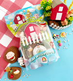 Toy set with a farm theme in packaging on a checkered tablecloth.