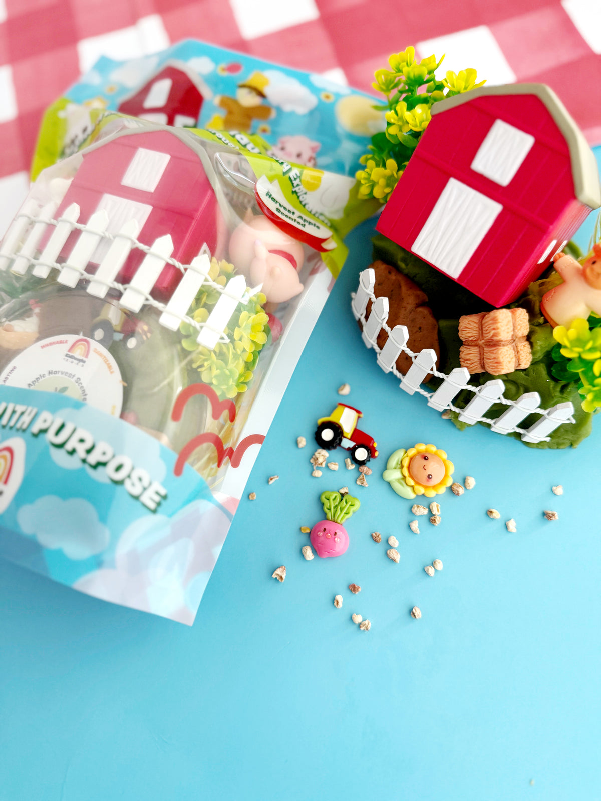 Toy farm set with a red barn, green grass, and small figures on a blue background.