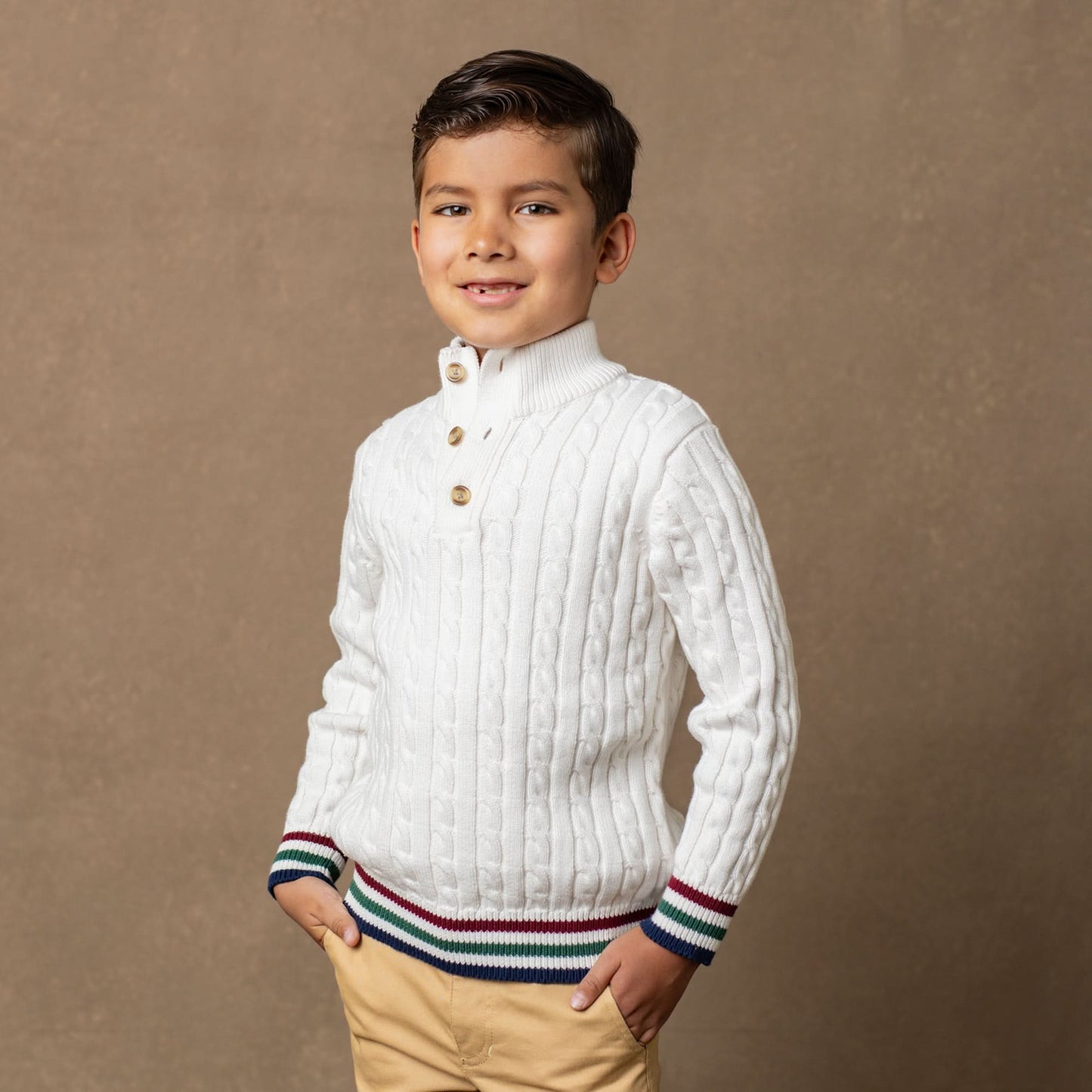 Young boy wearing a white sweater with a brown background