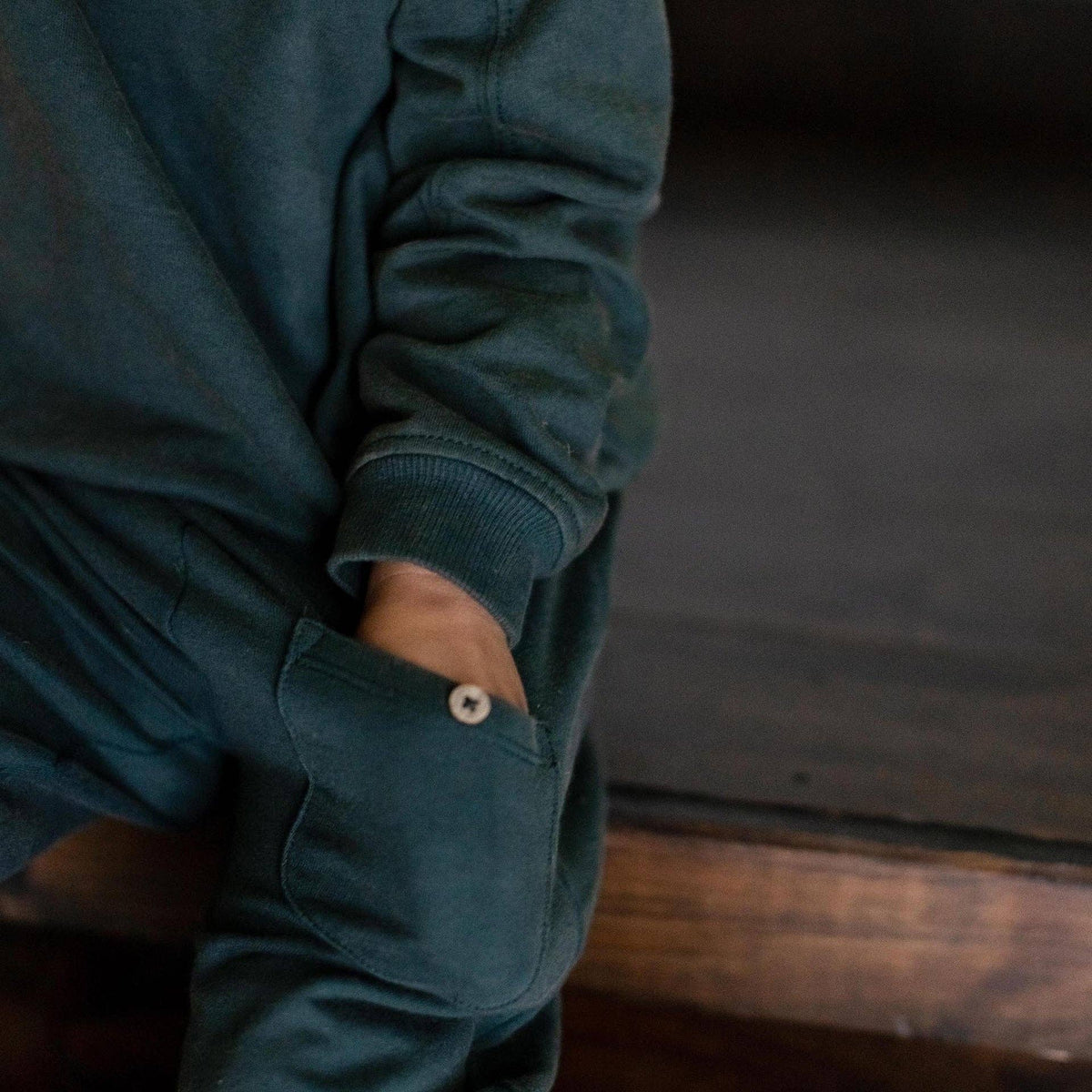 child wearing a dark green jogger set with a button.