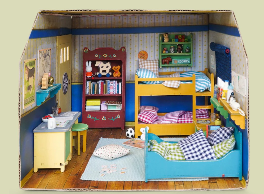 Dollhouse bedroom set with furniture and accessories inside a cardboard box