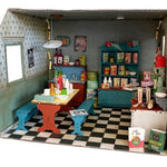 Diorama of a room with furniture and decor, including a table and chairs, bookshelf, and checkered floor.
