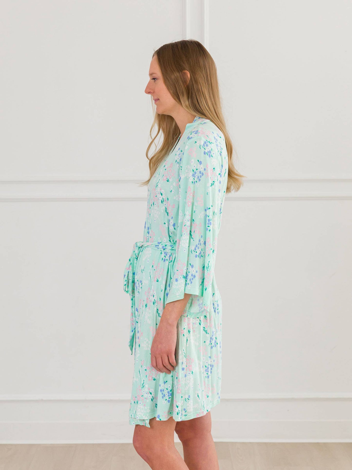 Woman wearing a light green floral robe against a white background
