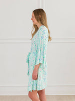 Woman wearing a light green floral robe against a white background