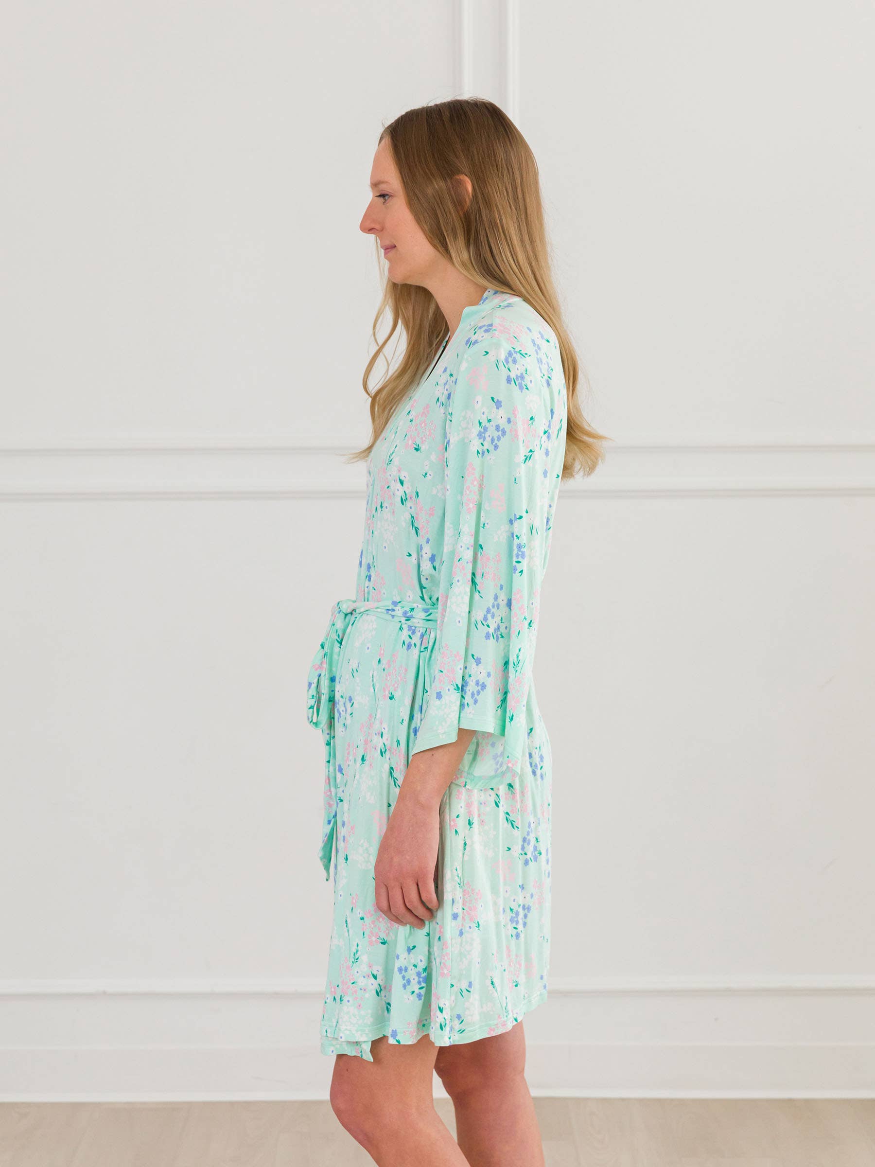 Woman wearing a light green floral robe against a white background