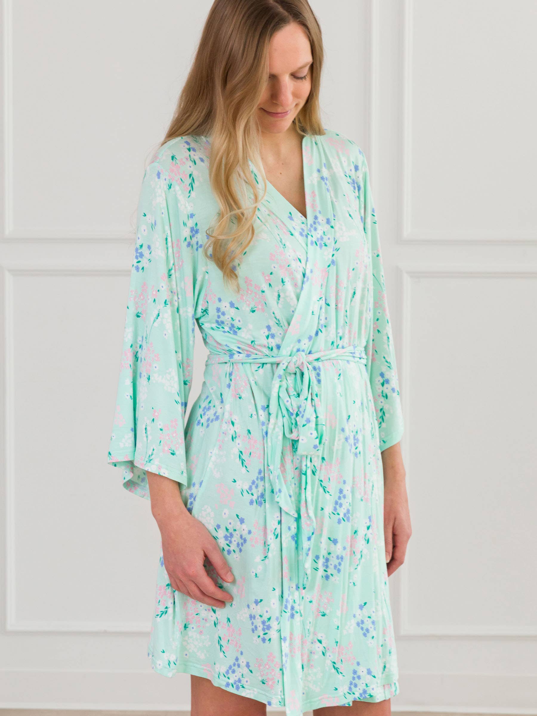 Woman wearing a light green floral robe against a white background