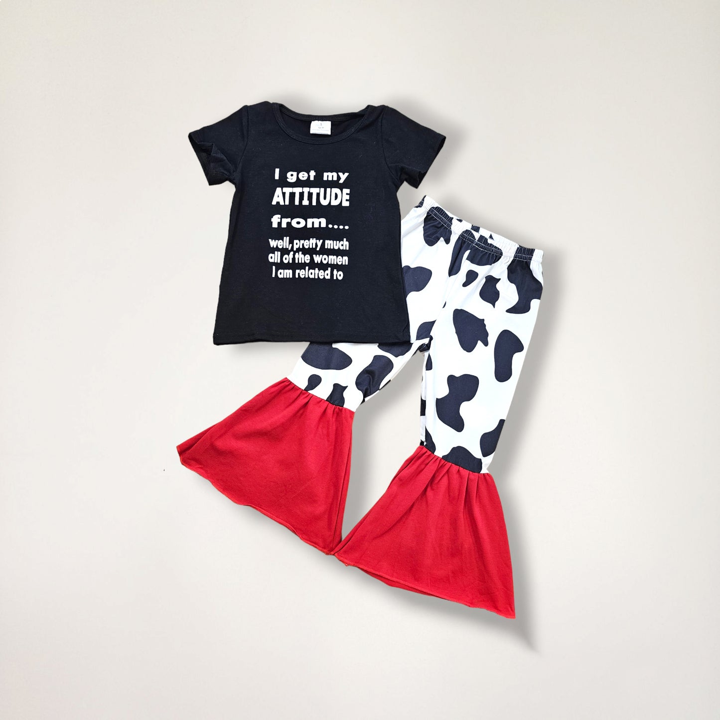 Black shirt with funny attitude text. Cow print with red bell bottom pants.