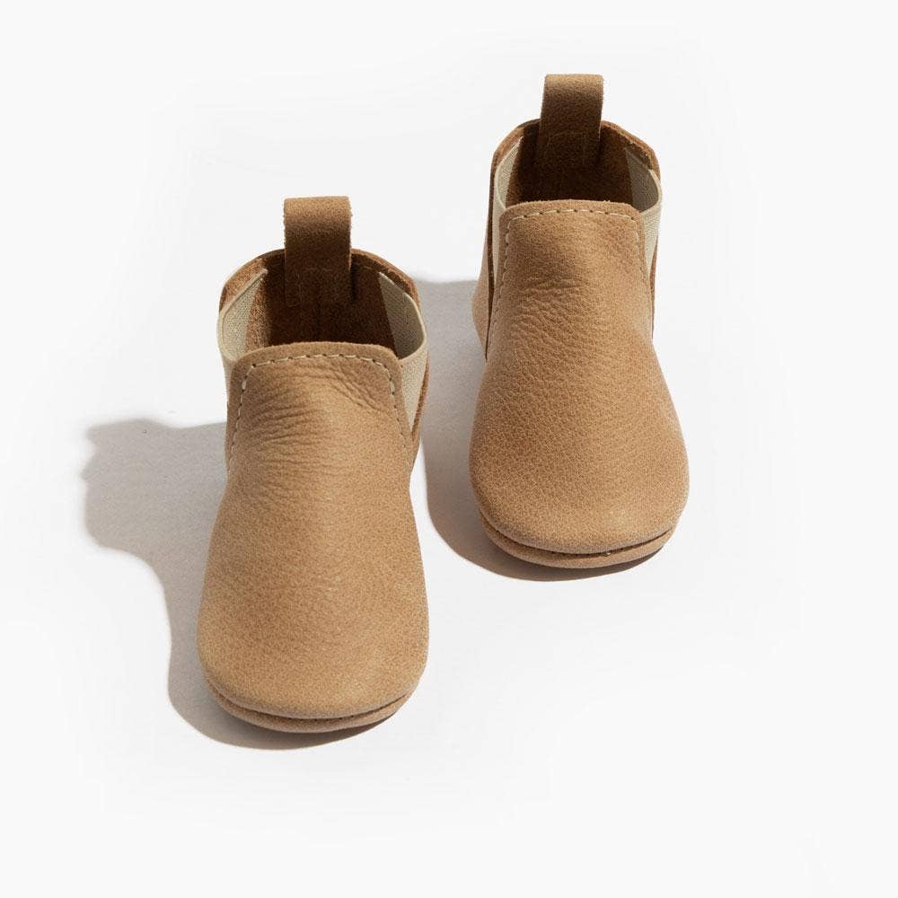 Pair of tan baby shoes on a white background