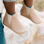 Close-up of beige baby shoes on a blurred natural background