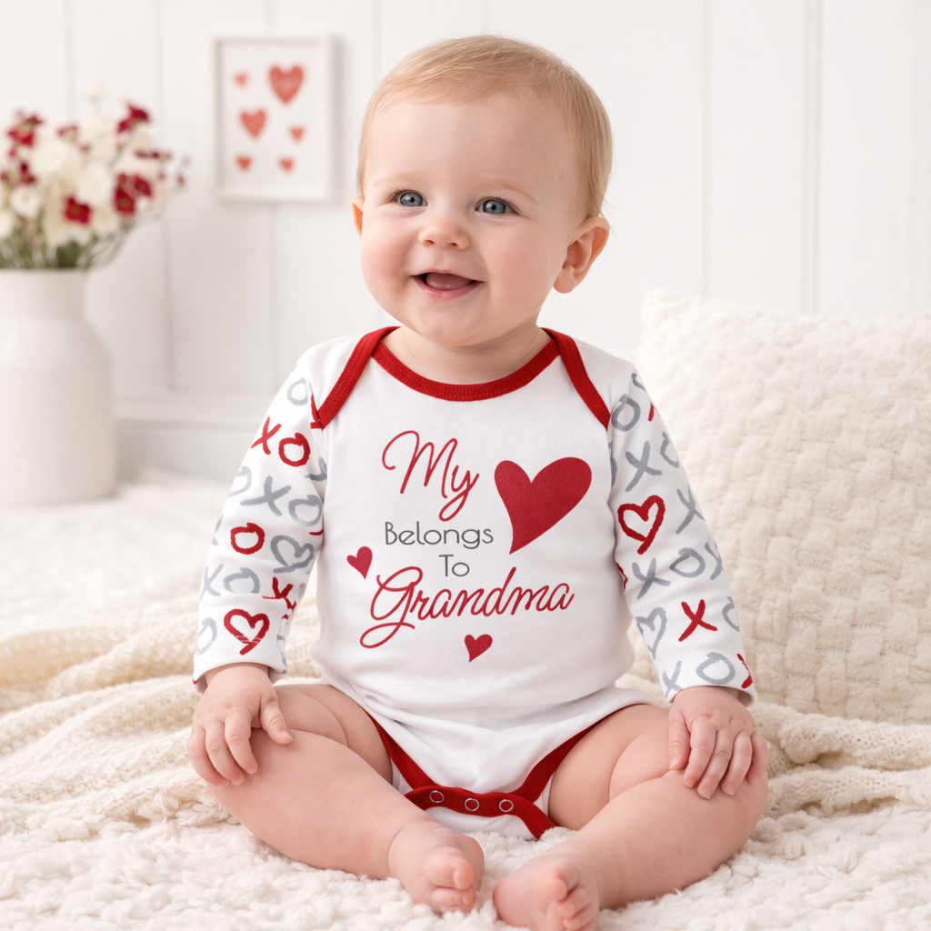 Baby wearing a bodysuit romper with 'My heart belongs to Grandma' text and red hearts, sitting on a soft surface.