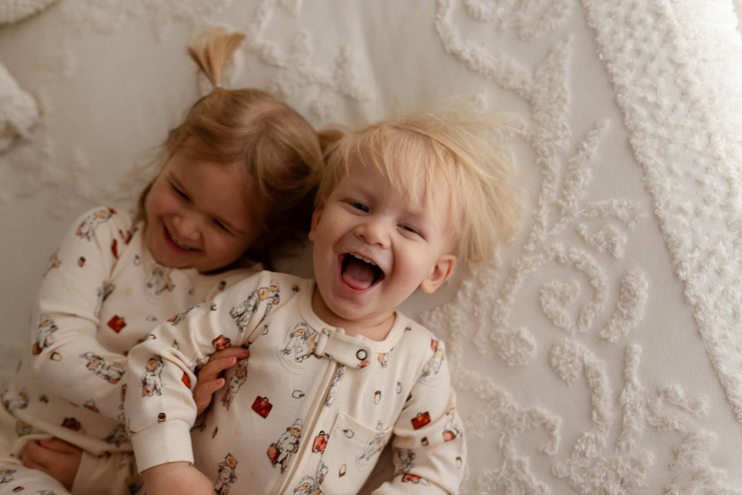 Two children in matching pajamas lying on a textured surface