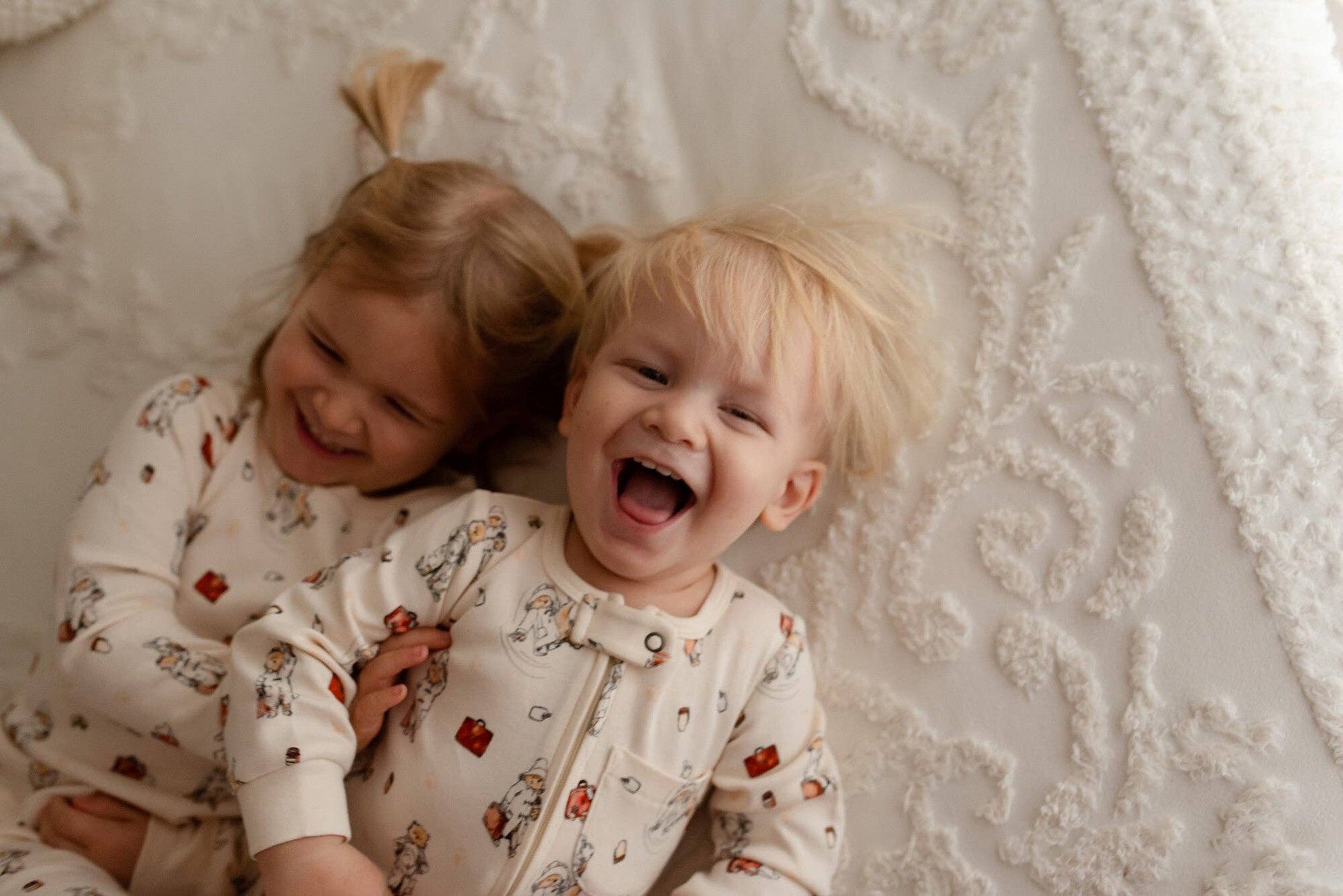 Two children in matching pajamas lying on a textured surface