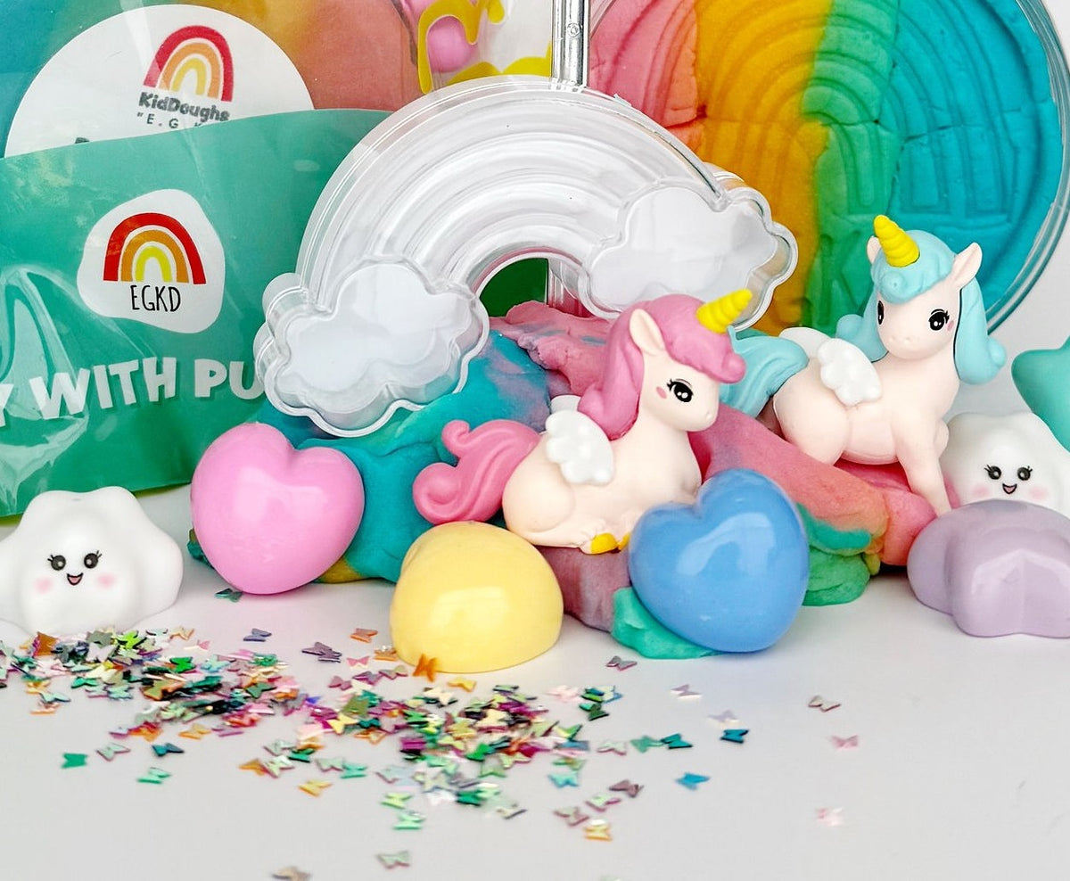 Colorful toys including a unicorn and cloud-shaped figures with confetti on a white background.