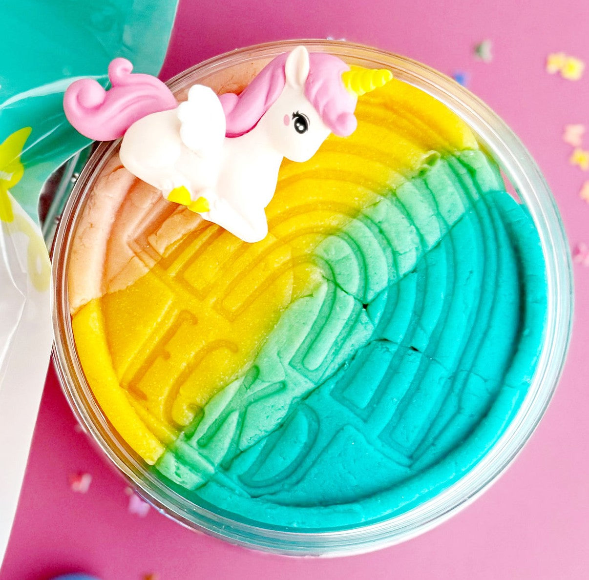 Colorful slime with a unicorn charm on a pink background